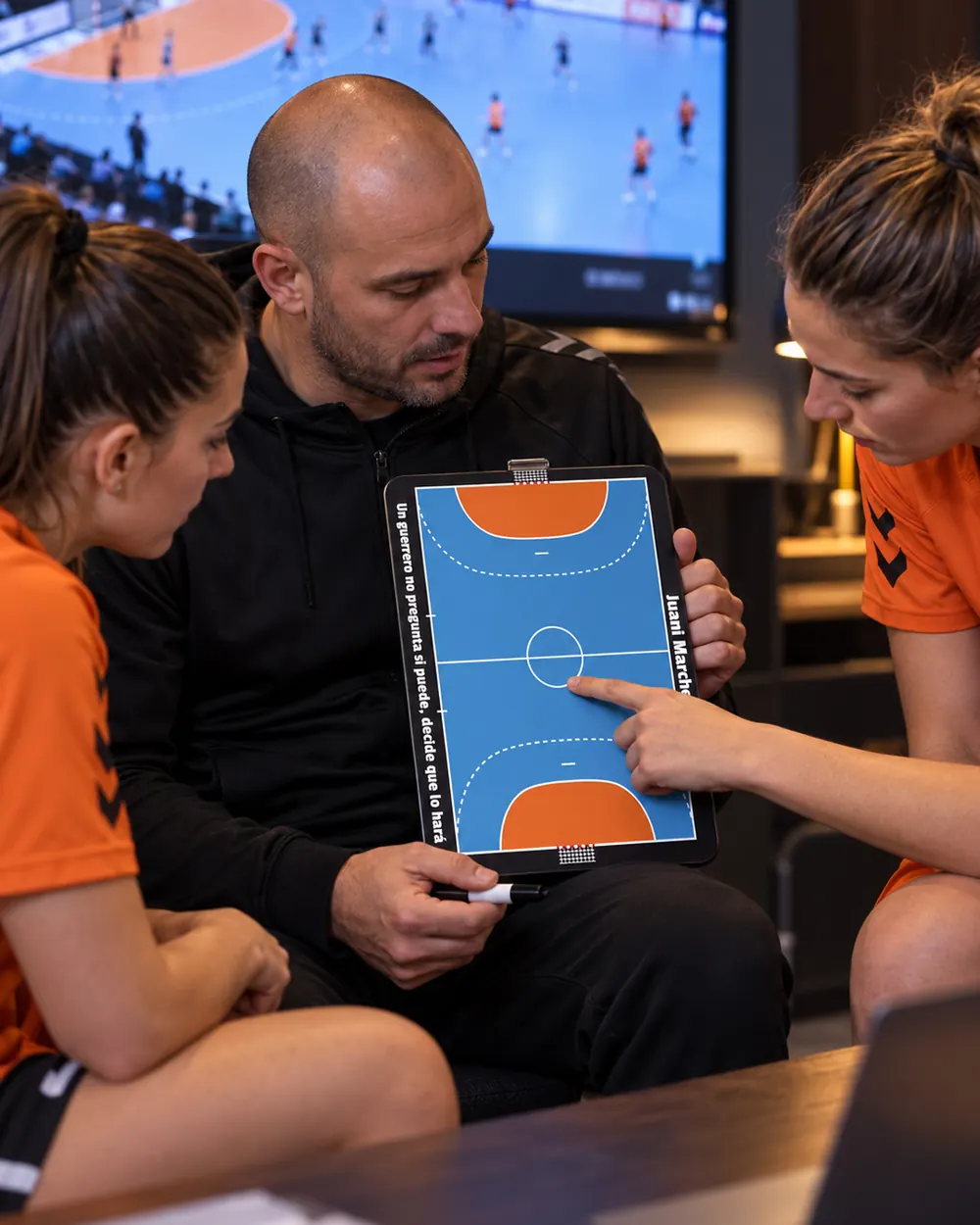 Um treinador de andebol revê a tática no quadro com as suas jogadoras